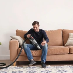 A man clean sofa with vacuum